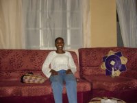 Phyllis sitting on her sofa, with a lit candle beside her